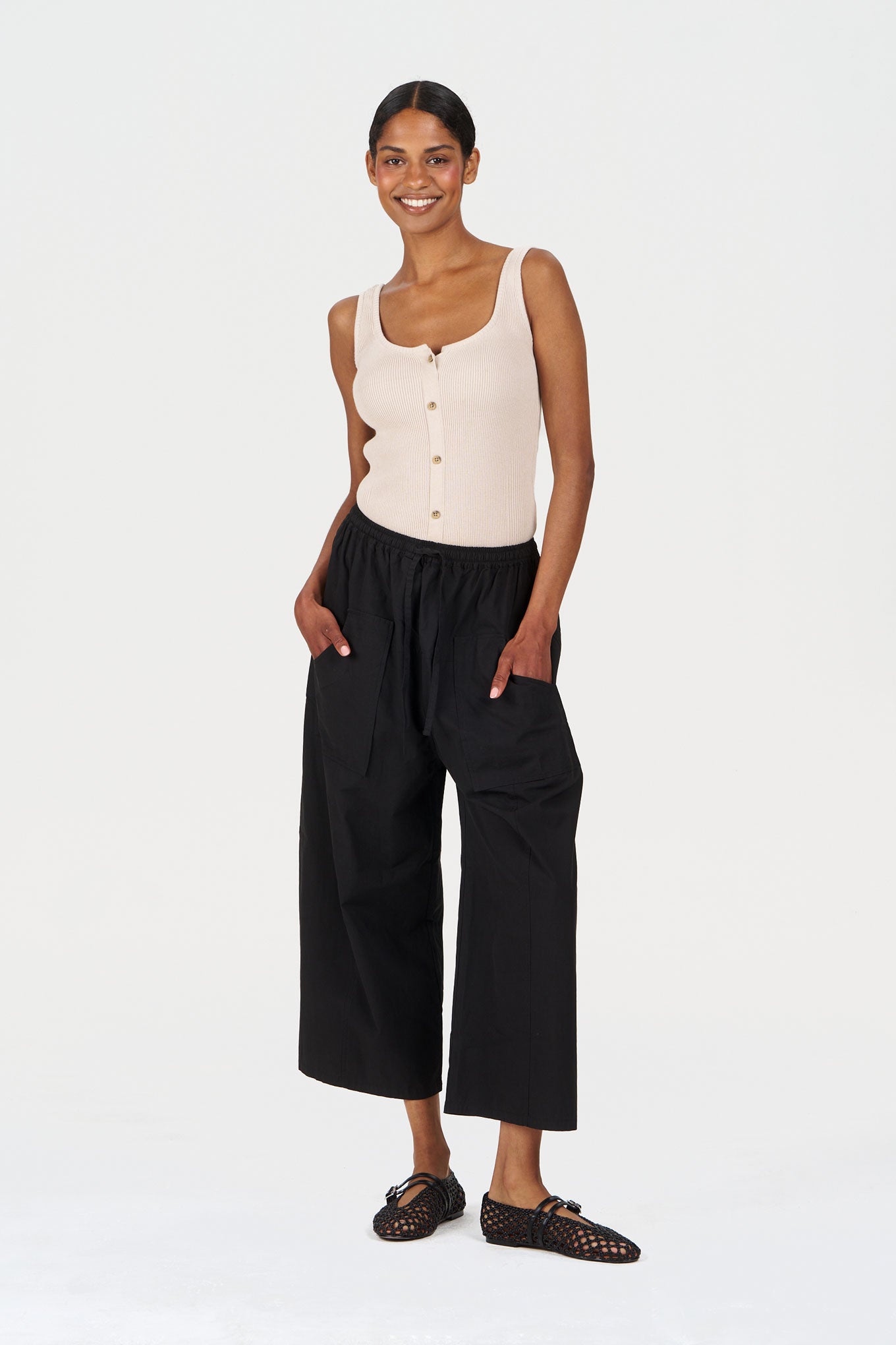 Model wearing CLEO Organic Cotton Trouser - Black paired with a light tank top and stylish footwear.