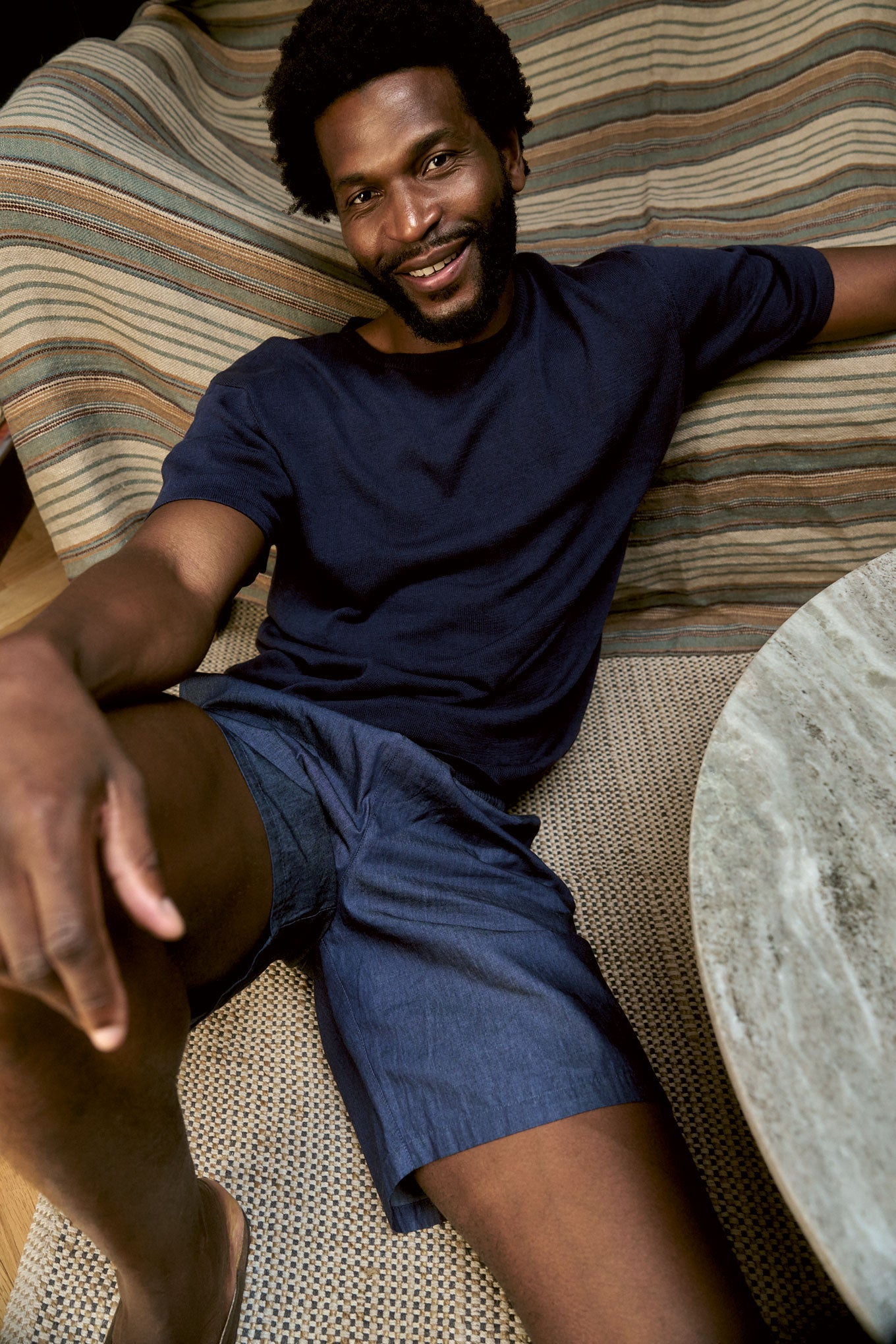 WALT Organic Ramie Cotton Tee - Navy worn by a man sitting comfortably on a couch, showcasing its breathable fabric and loose fit.