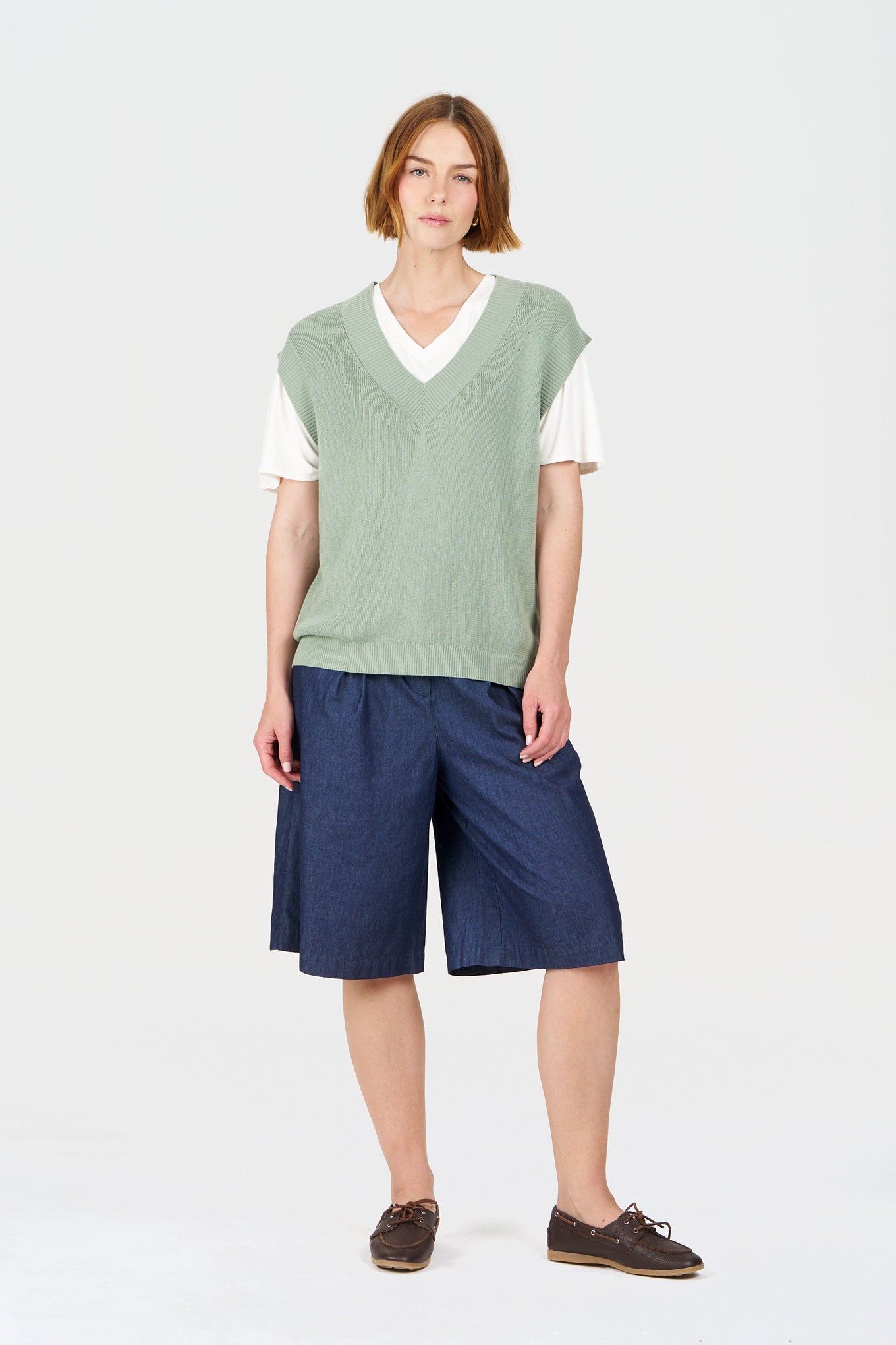 Woman wearing LIV Organic Cotton Short - midwash with a green sweater vest and stylish brown shoes.