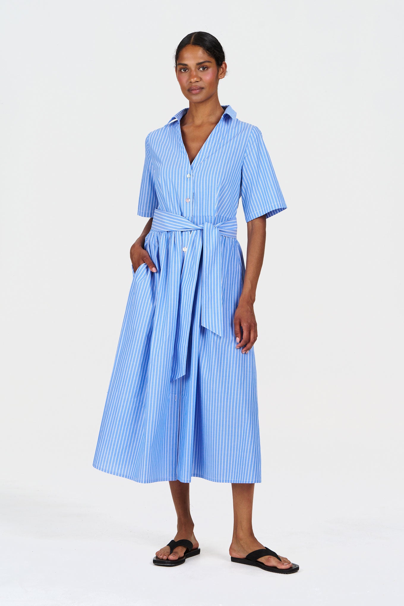 Model wearing SHORE Organic Cotton Dress - Blue Stripe, featuring a belted waist and button-down front in blue stripes.