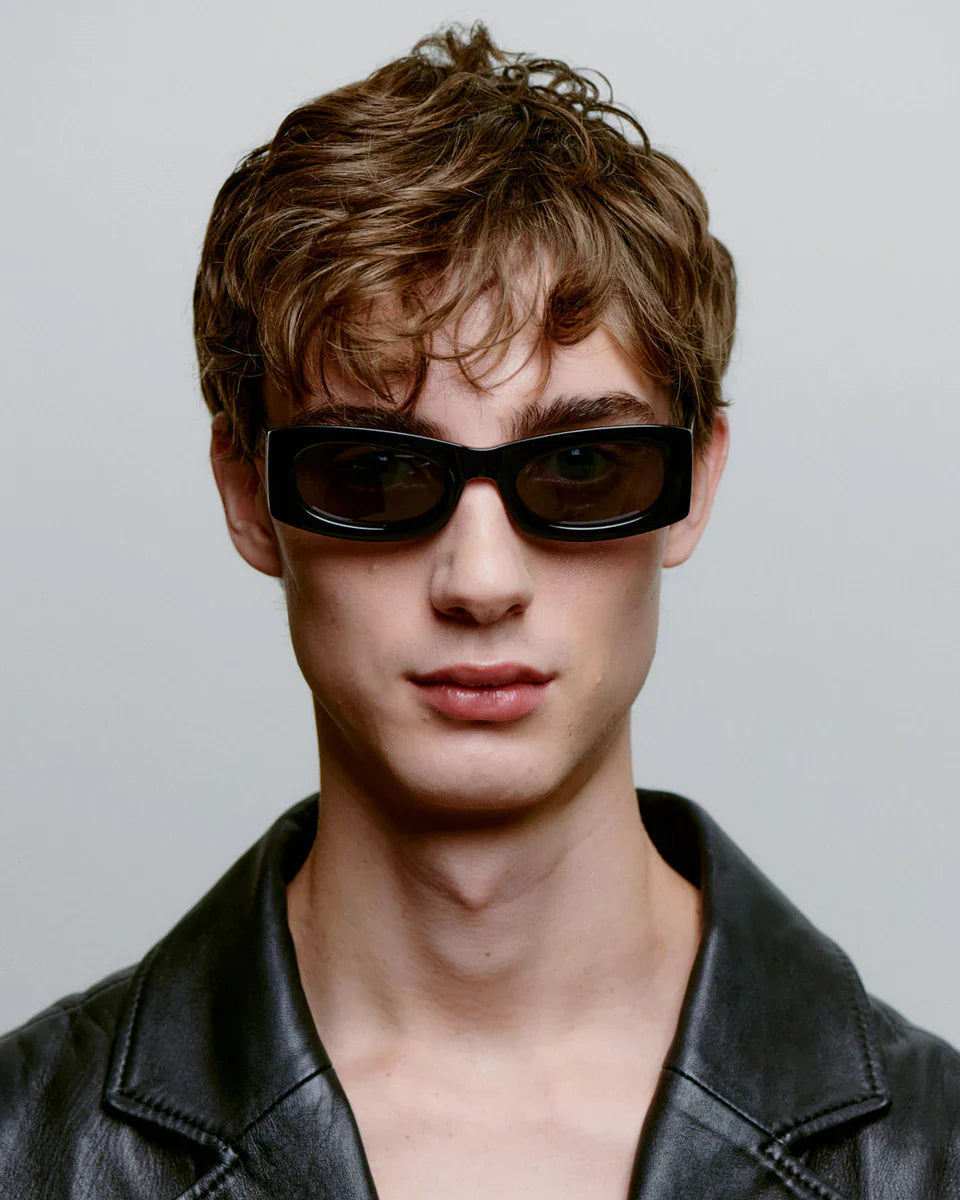 FRIDA - Black Sunglasses by A.Kjaerbede worn by a model, showcasing the cateye effect and sleek design.