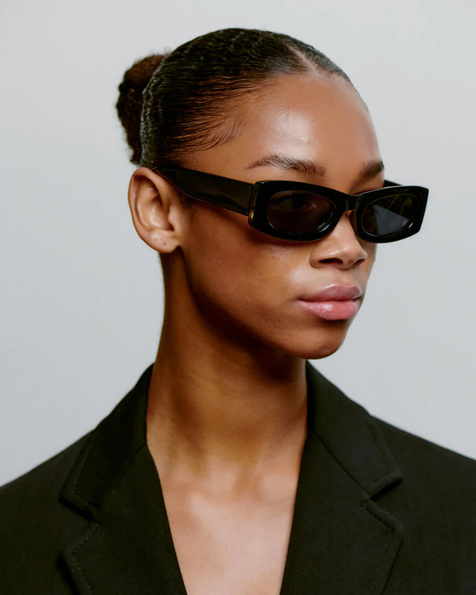 Model wearing FRIDA - Black Sunglasses by A.Kjaerbede showcasing a sleek cateye design and UV protection.