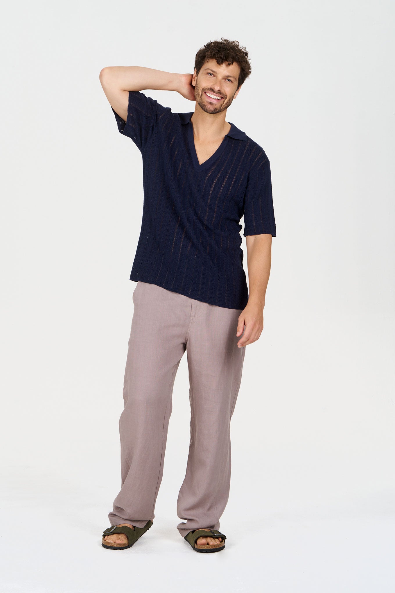 A smiling man wearing a navy V-neck shirt and camel MAKULU Tencel Linen Trouser - Camel, showcasing a relaxed look.