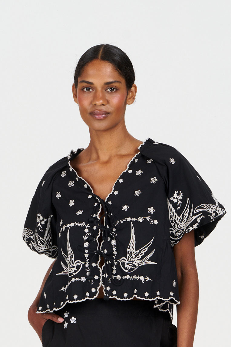 Model wearing the BEATRIX Organic Cotton Top - Black featuring intricate embroidery and a stylish design.