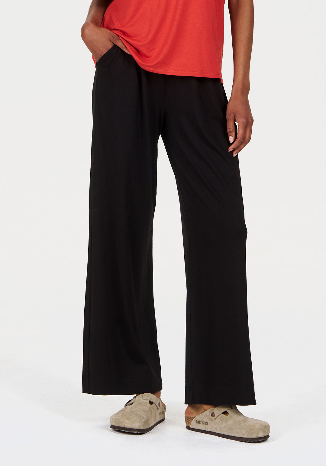 Model wearing BINITA Modal Trouser - Black with a red top and beige clogs, showcasing the stylish and comfortable fit.