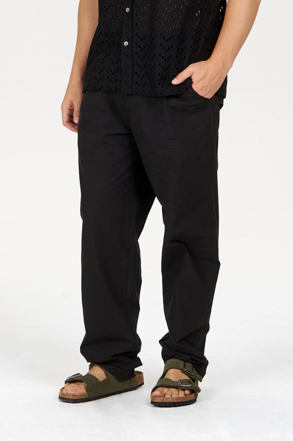 Model wearing BOWIE Organic Cotton Trouser - Black with a loose fit and casual sandals.