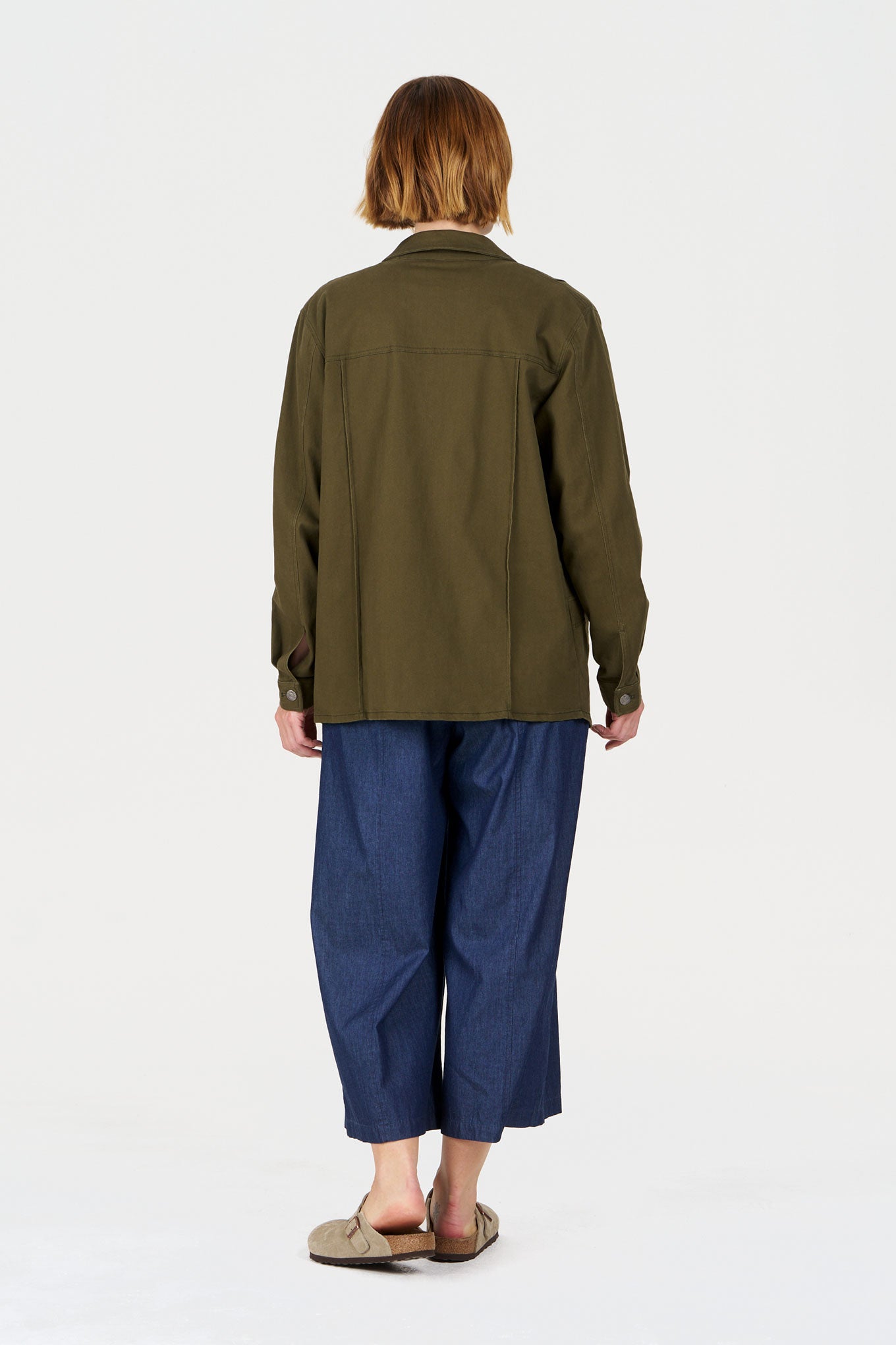 Back view of a person wearing the CHORE Organic Cotton Jacket - khaki paired with denim pants.