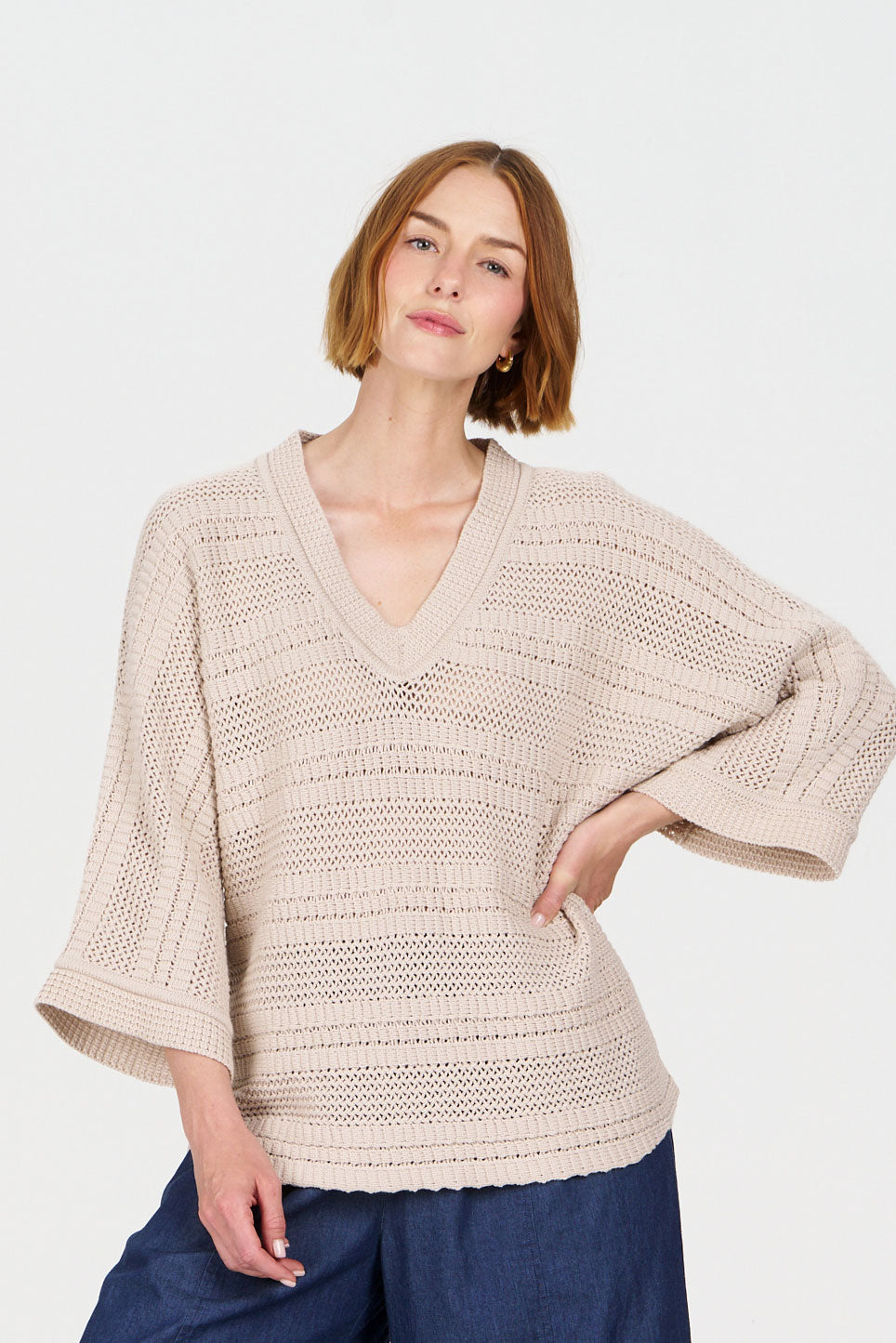 Model wearing the COLADA Organic Cotton Tee - Sand, featuring a relaxed fit and V-neck design, with a light beige color.