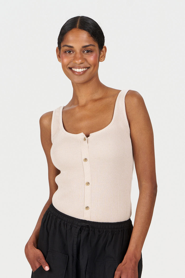 COVE Vest Organic Cotton Vest - Sand worn by a smiling model, showcasing a stylish design and sustainable materials.