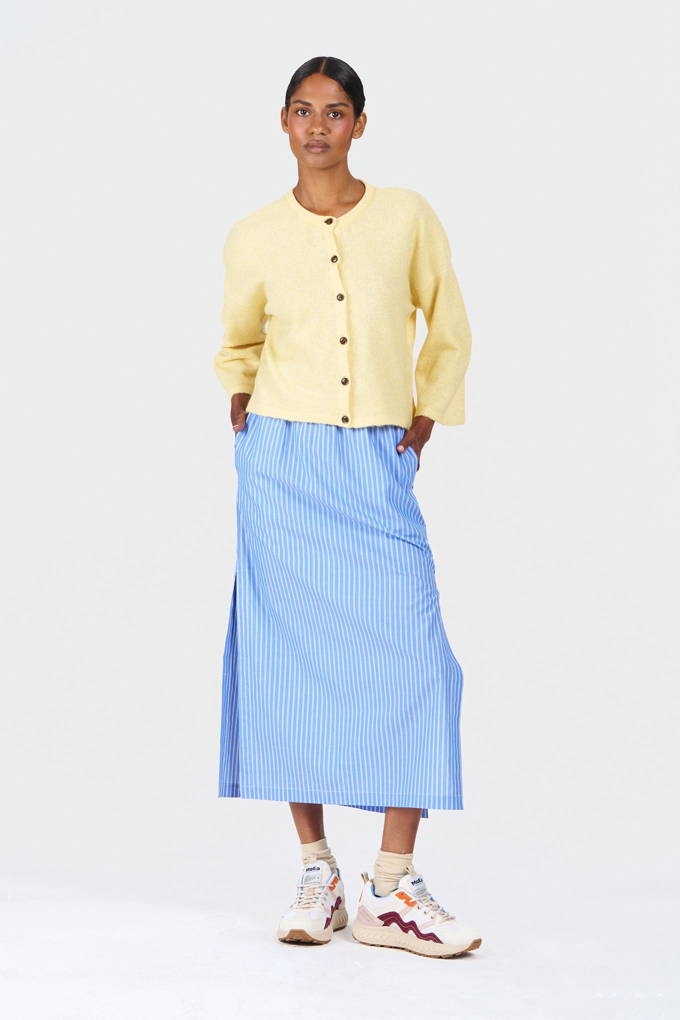 Model wearing LIELA Organic Cotton Skirt - Blue Stripe with a yellow cardigan and sneakers.