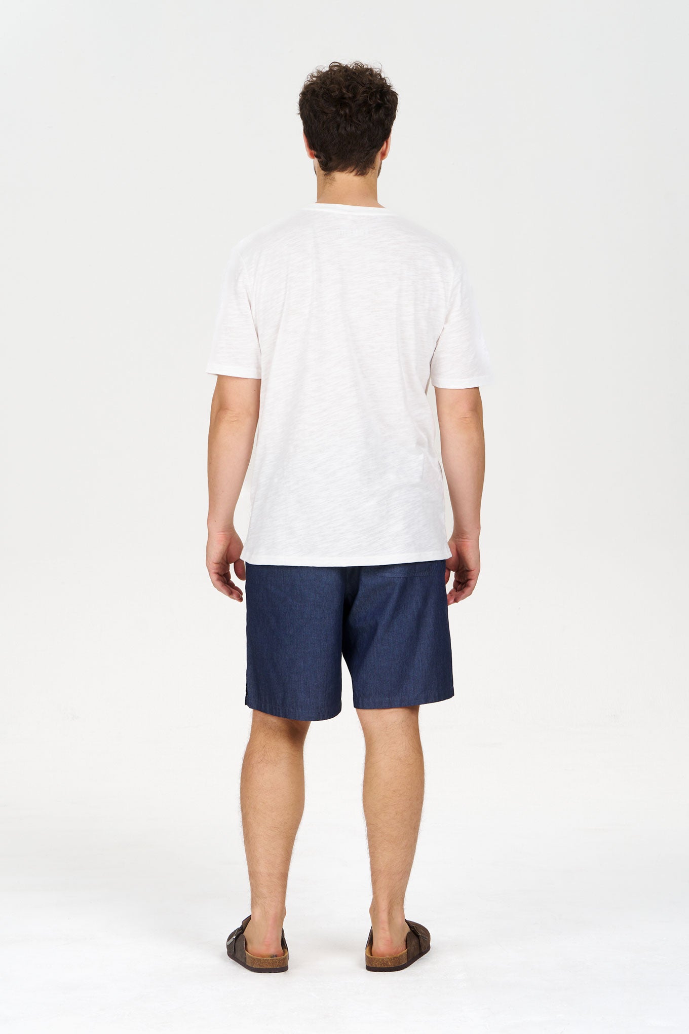 Model wearing JERRY Organic Cotton Short - Mid Wash with a plain white t-shirt from the back view.