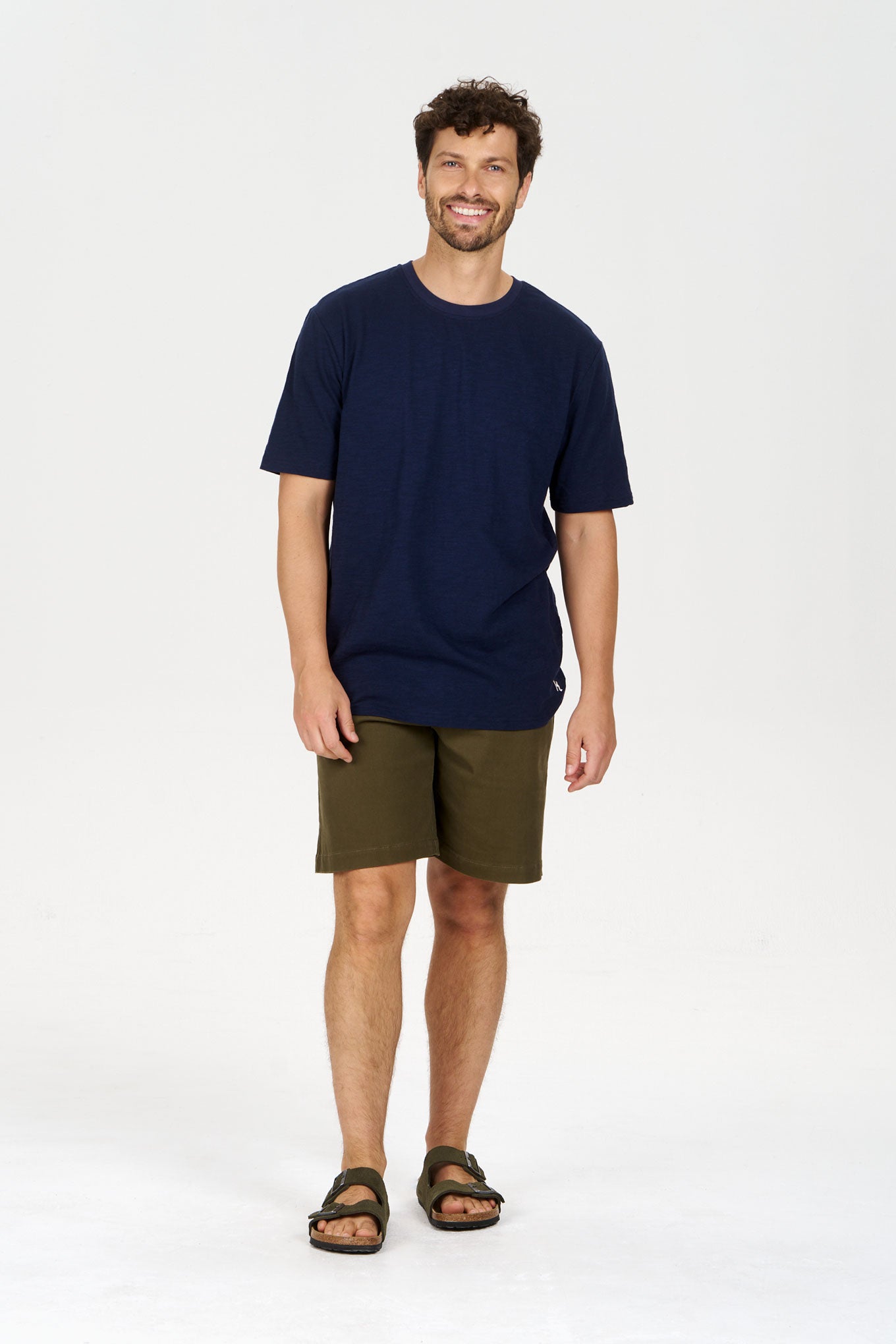Man wearing JAMBO Organic Cotton Twill Short - Green with a navy t-shirt and sandals.