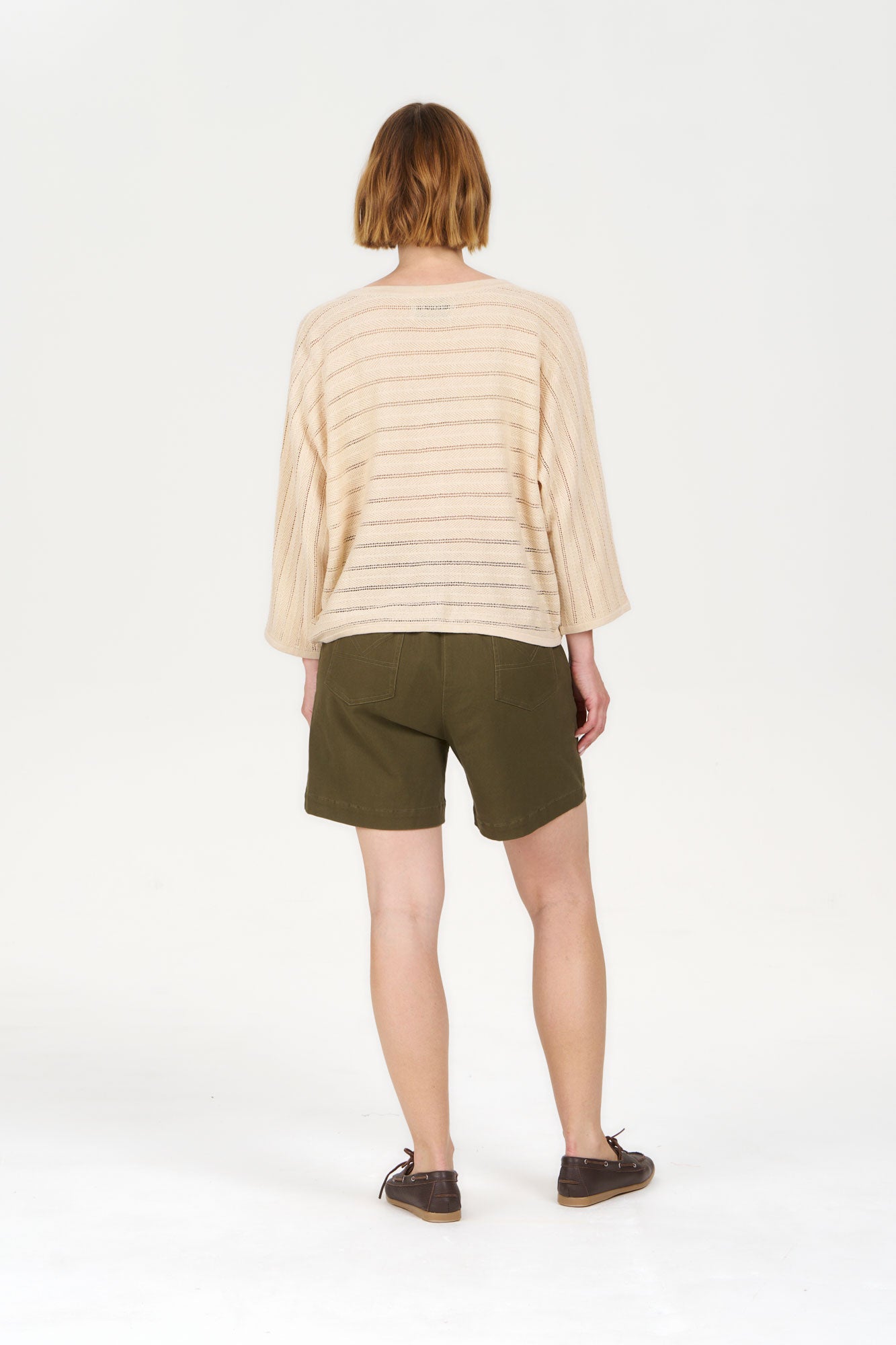 Model wearing MALI Organic Ramie Cotton Batwing Cardigan - Sand with olive green shorts from the back.
