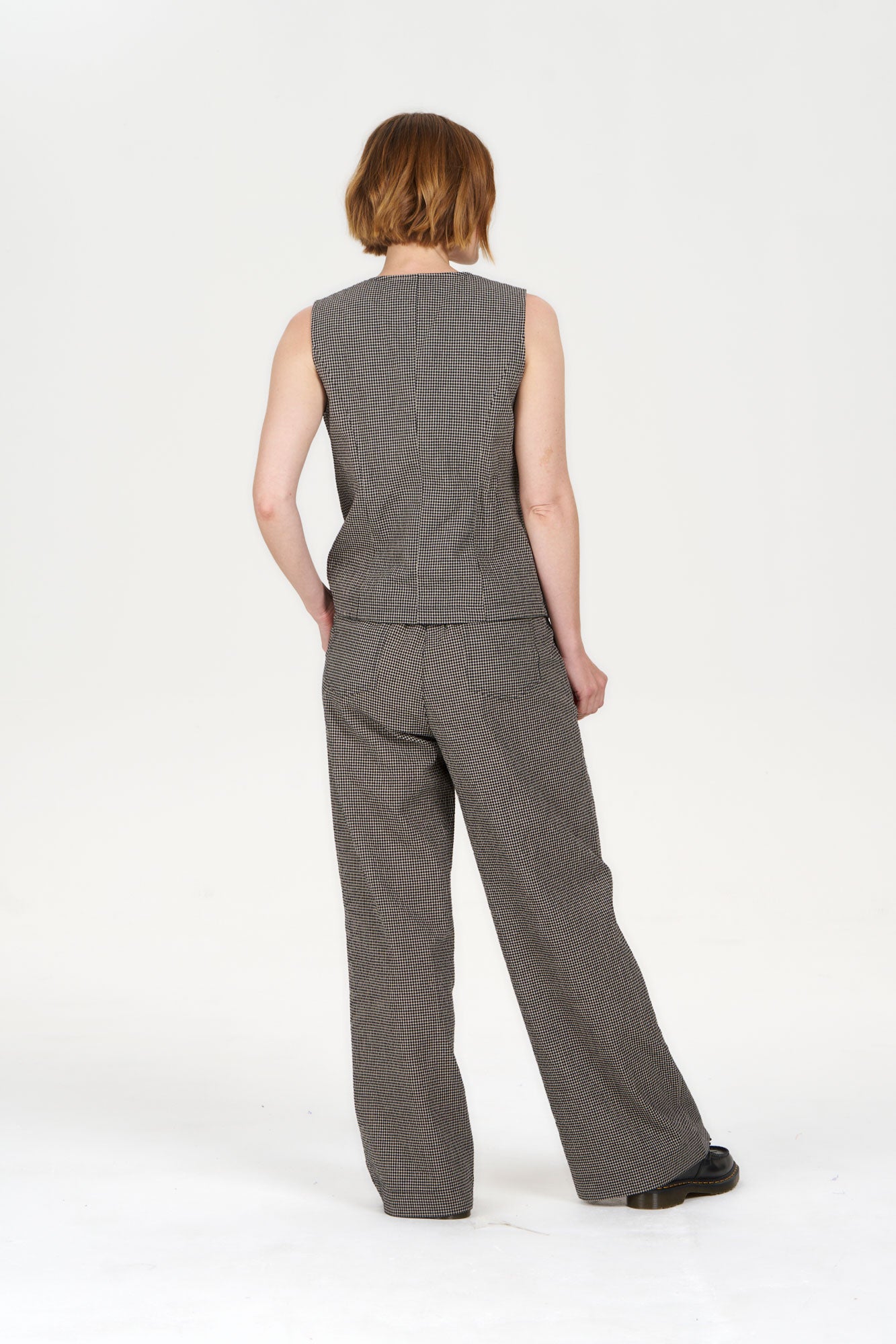 Back view of model wearing TESSA Organic Cotton Vest - check with matching pants in a houndstooth pattern.