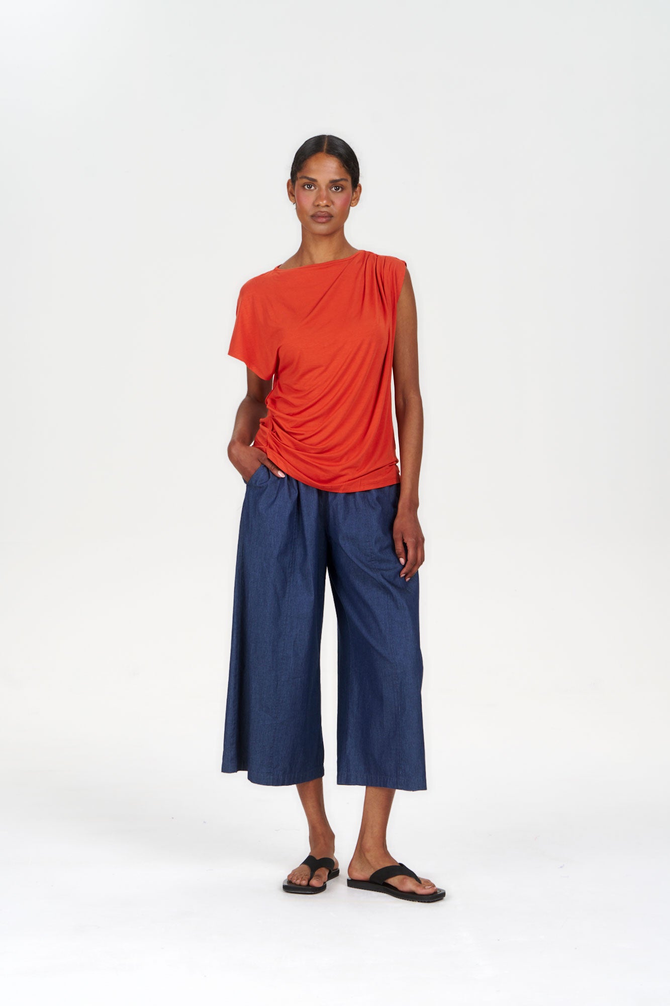 Model wearing CATE Modal Top - Orange paired with blue culottes and sandals, showcasing a stylish and comfortable outfit.