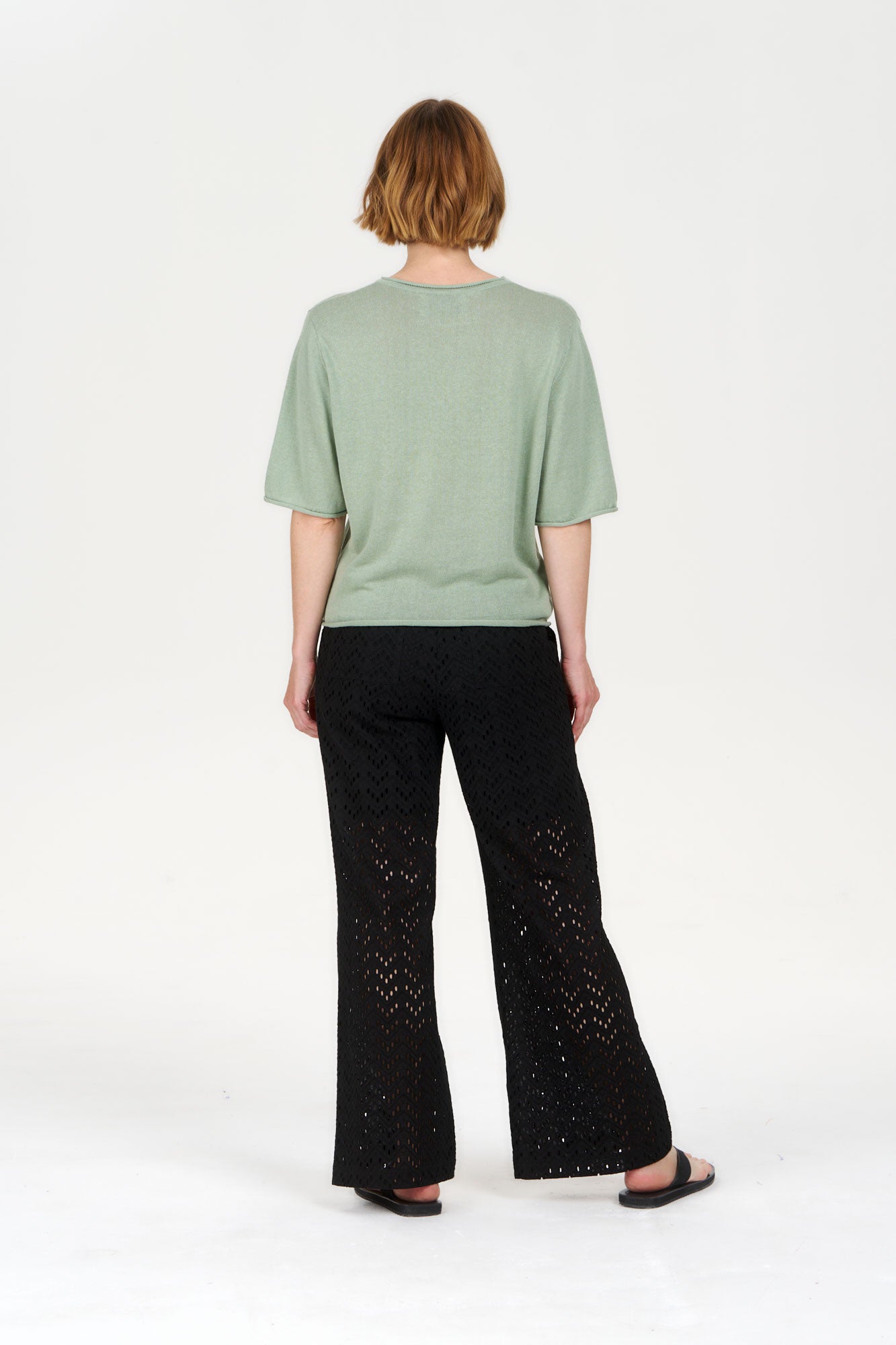 Model wearing CAMILLE Organic Ramie Cotton Tee - Sage with black pants from the back.