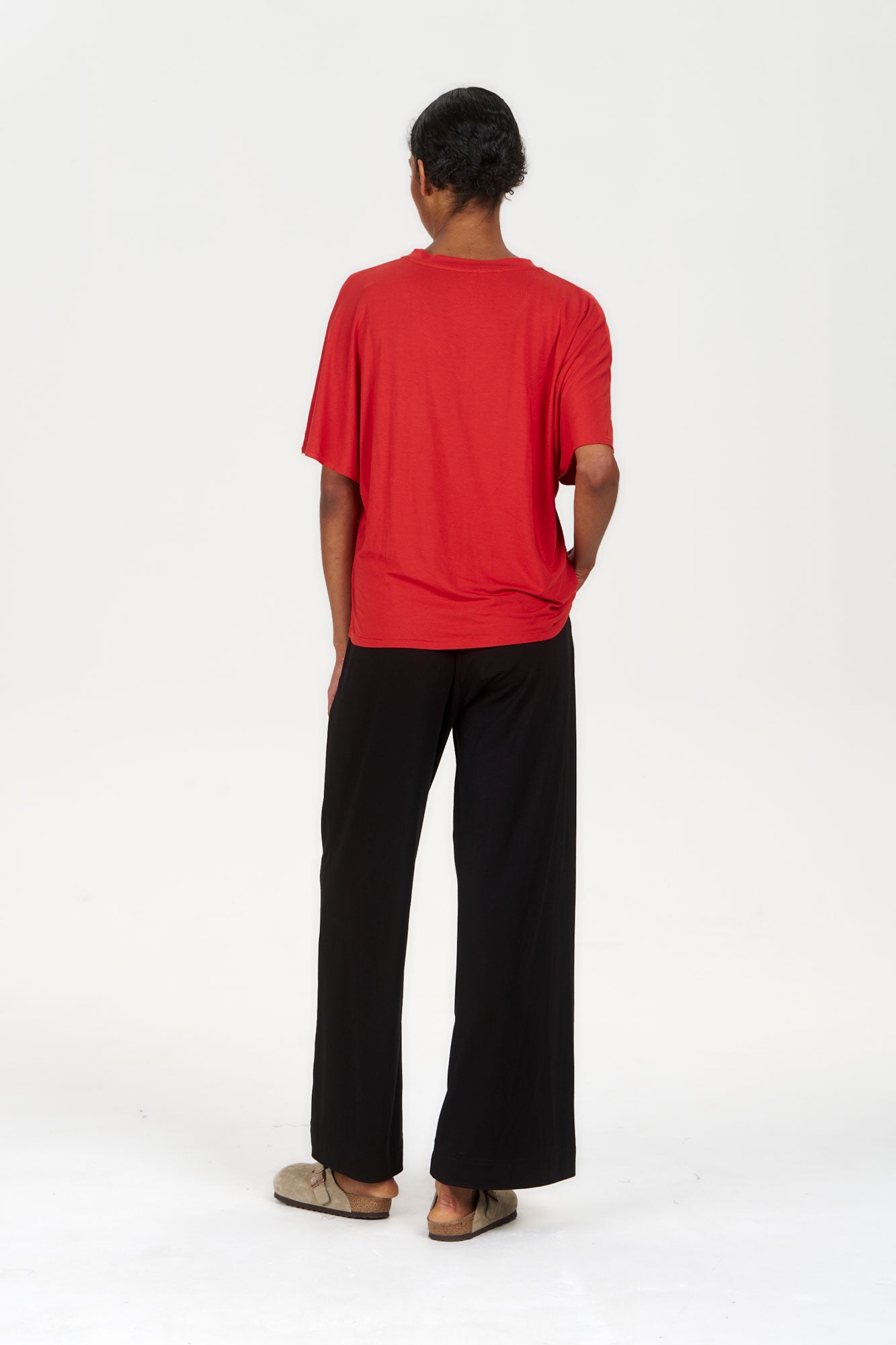 Model wearing BINITA Modal Trouser - Black paired with a red top, viewed from the back against a plain white background.