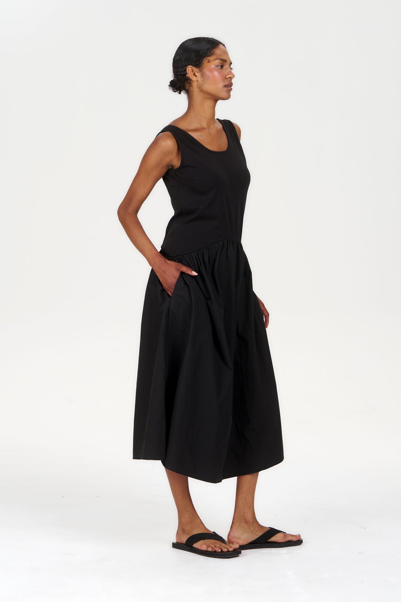 Model wearing NEEMA Organic Cotton Dress - Black, featuring a sleeveless design and side pockets.