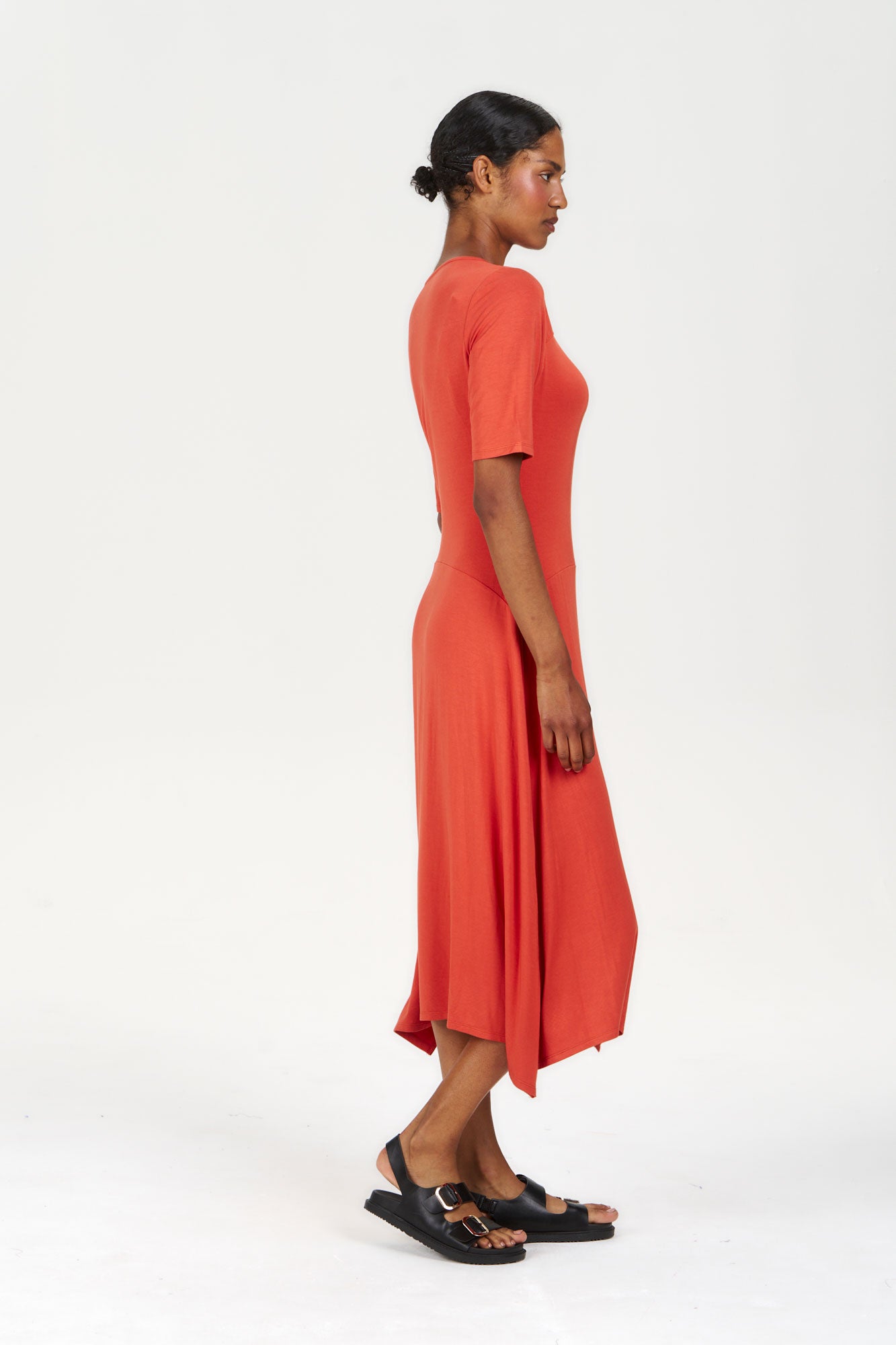 Side view of a model wearing the PIP Modal Dress - Orange, showcasing its vegan fabric and stylish design.