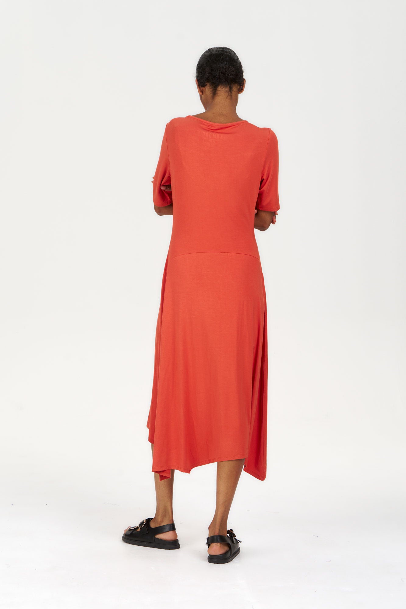 Model wearing the PIP Modal Dress - Orange from the back, showcasing its elegant design and flowing style.