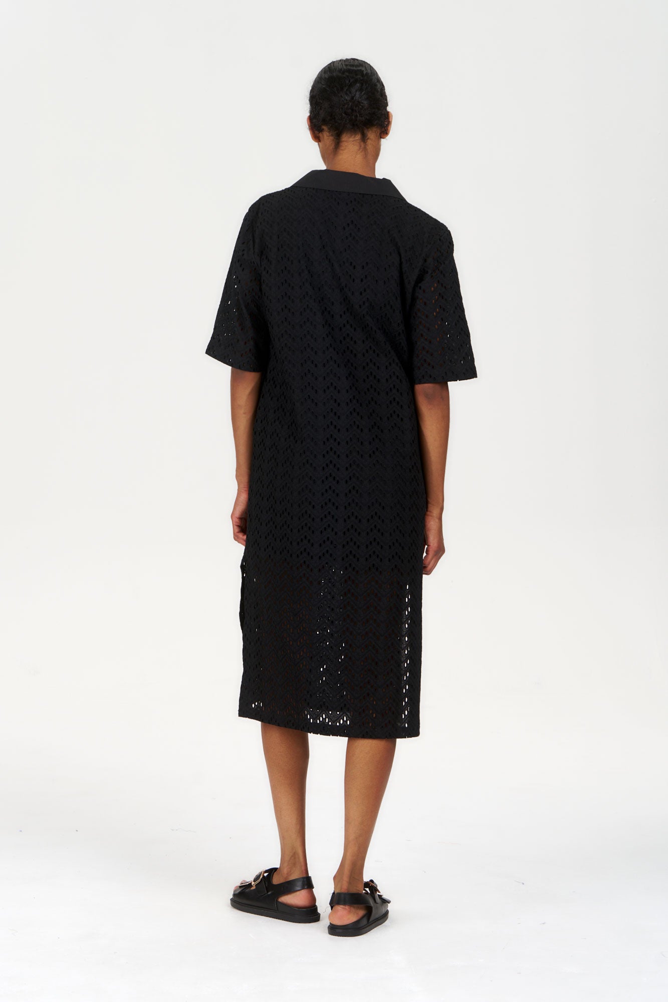 Back view of a woman wearing the DELILAH Organic Cotton Dress - Black, showcasing its stylish design and organic fabric.
