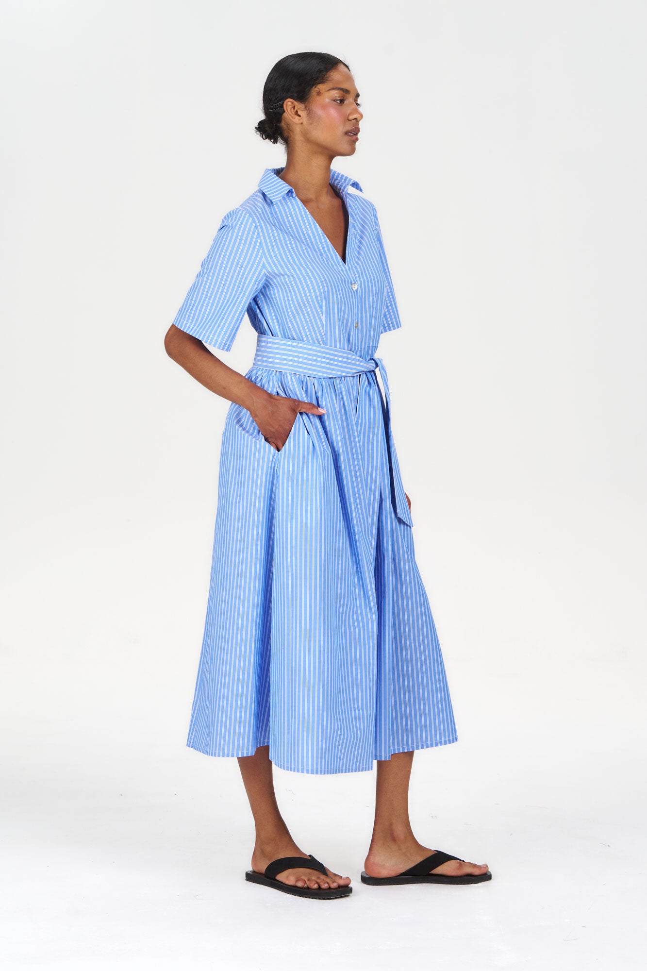 Model wearing SHORE Organic Cotton Dress - Blue Stripe with pockets and short sleeves, styled with sandals.