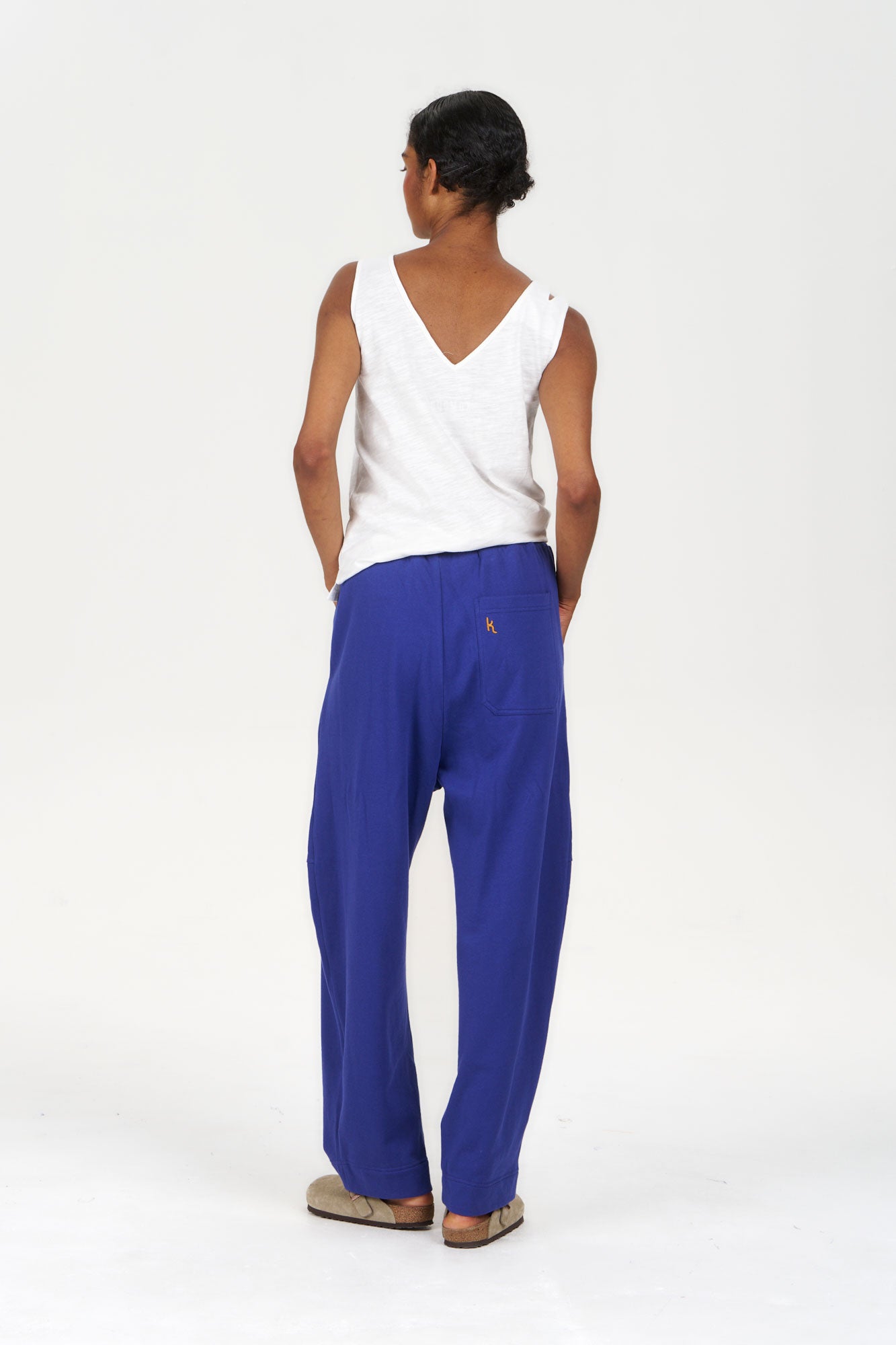 MARA Organic Cotton Jogger - Blue worn by a model from the back, paired with a white tank top and casual footwear.