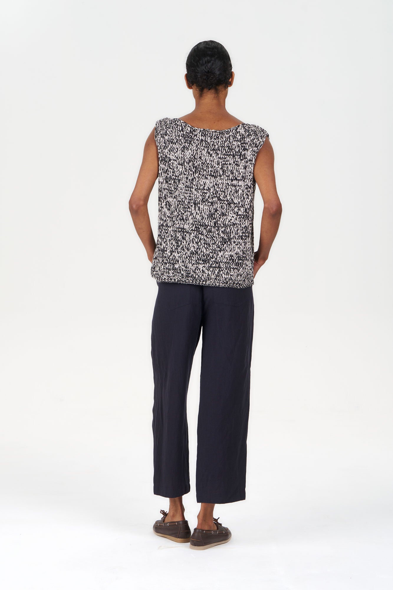 Back view of model wearing KALA Organic Cotton Vest - Black & White with loose black pants.