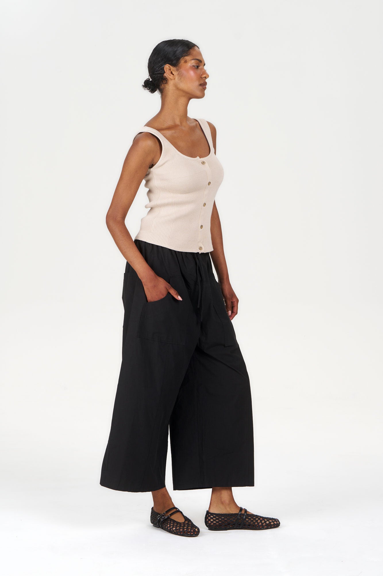 Woman wearing CLEO Organic Cotton Trouser - Black with a light tank top and stylish shoes.