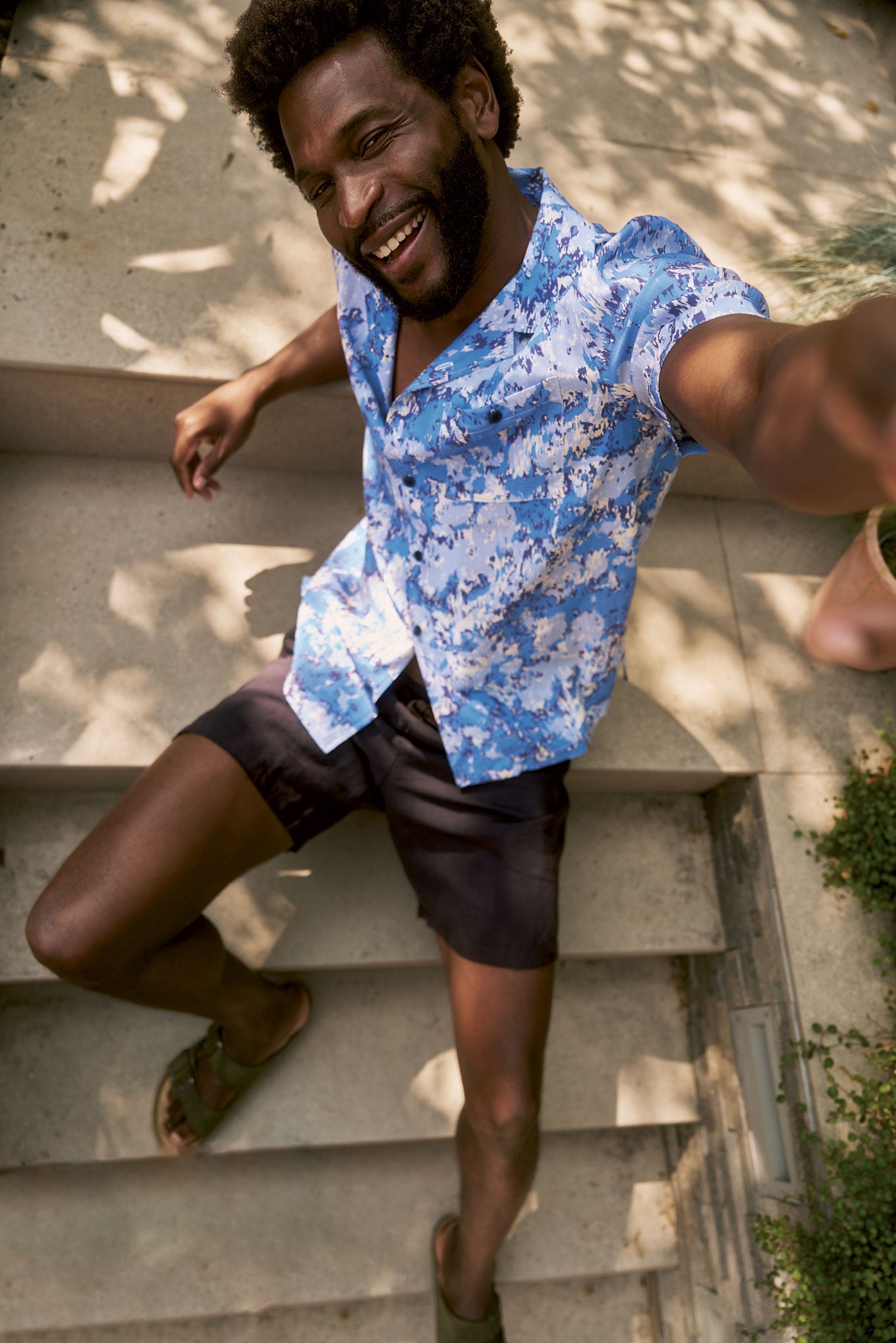 SPINDRIFT Printed Tencel Shirt - Acid Blue worn by a smiling man sitting on steps, featuring an abstract print and loose fit.
