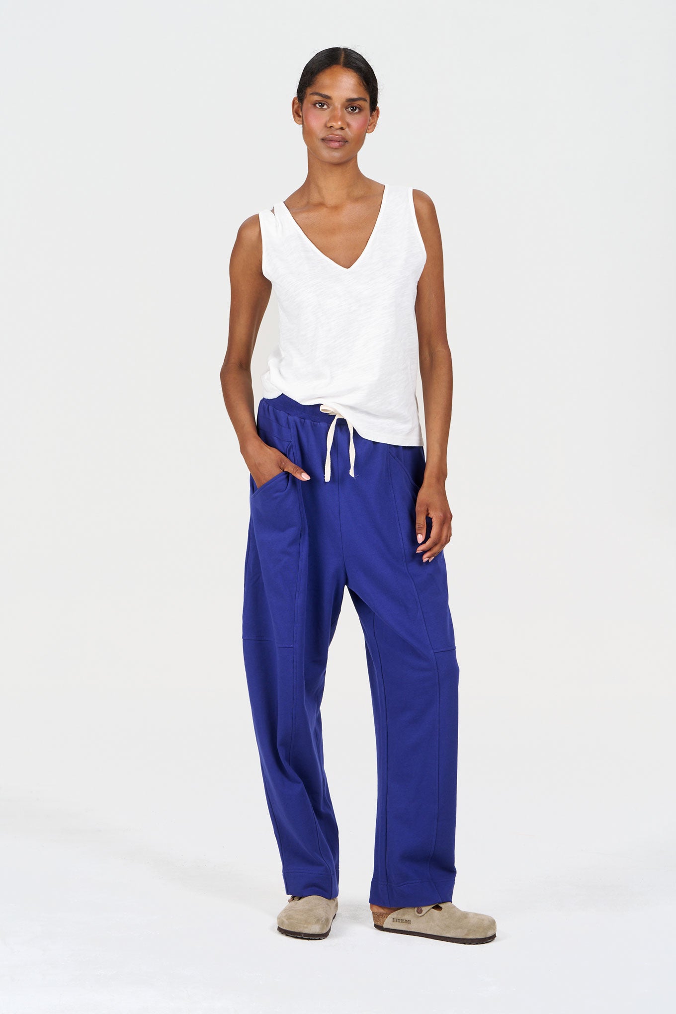 Woman wearing MARA Organic Cotton Jogger - Blue, styled with a white tank top and casual footwear.