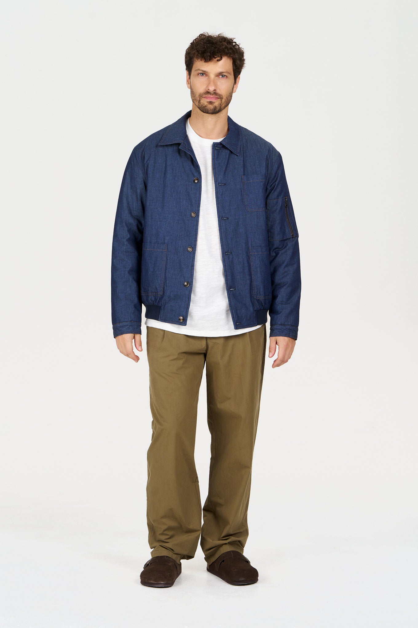 NILE Organic Cotton Chambray Jacket - Mid Wash modeled by a man in a casual setting showcasing its denim look.