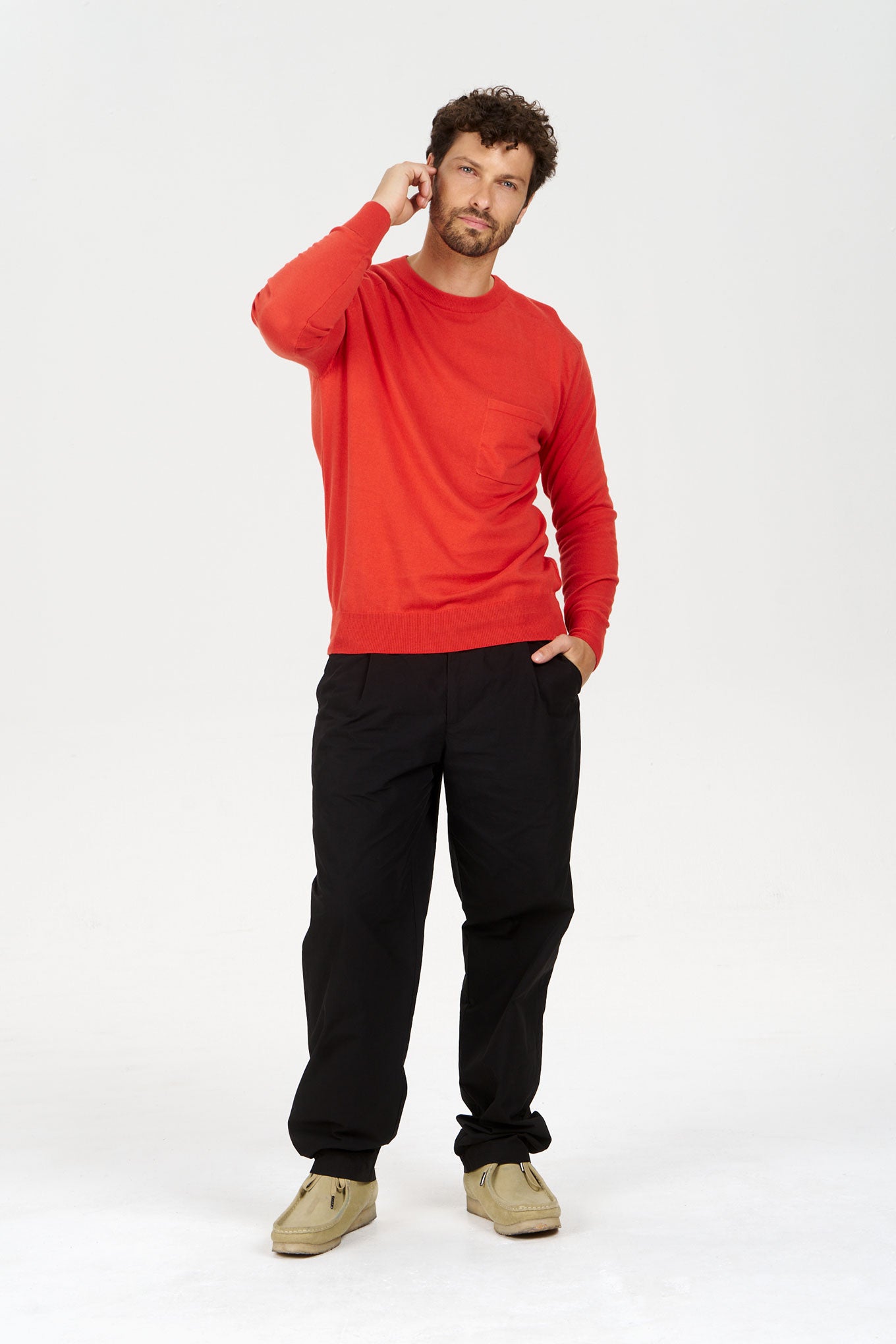 Man wearing a red POCKET GOTS Organic Cotton Jumper, styled with black pants