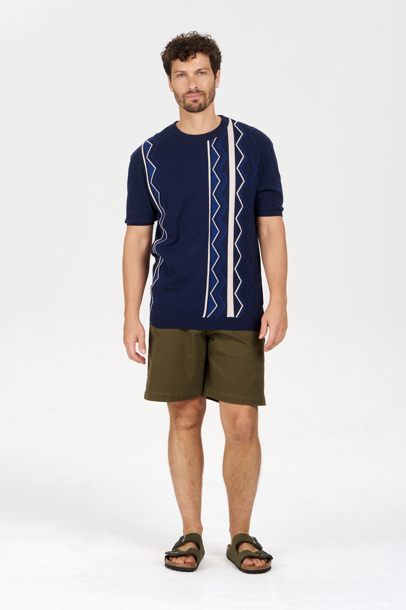 Model wearing a RAFFI Organic Cotton Tee with a geometric design, paired with shorts and sandals.