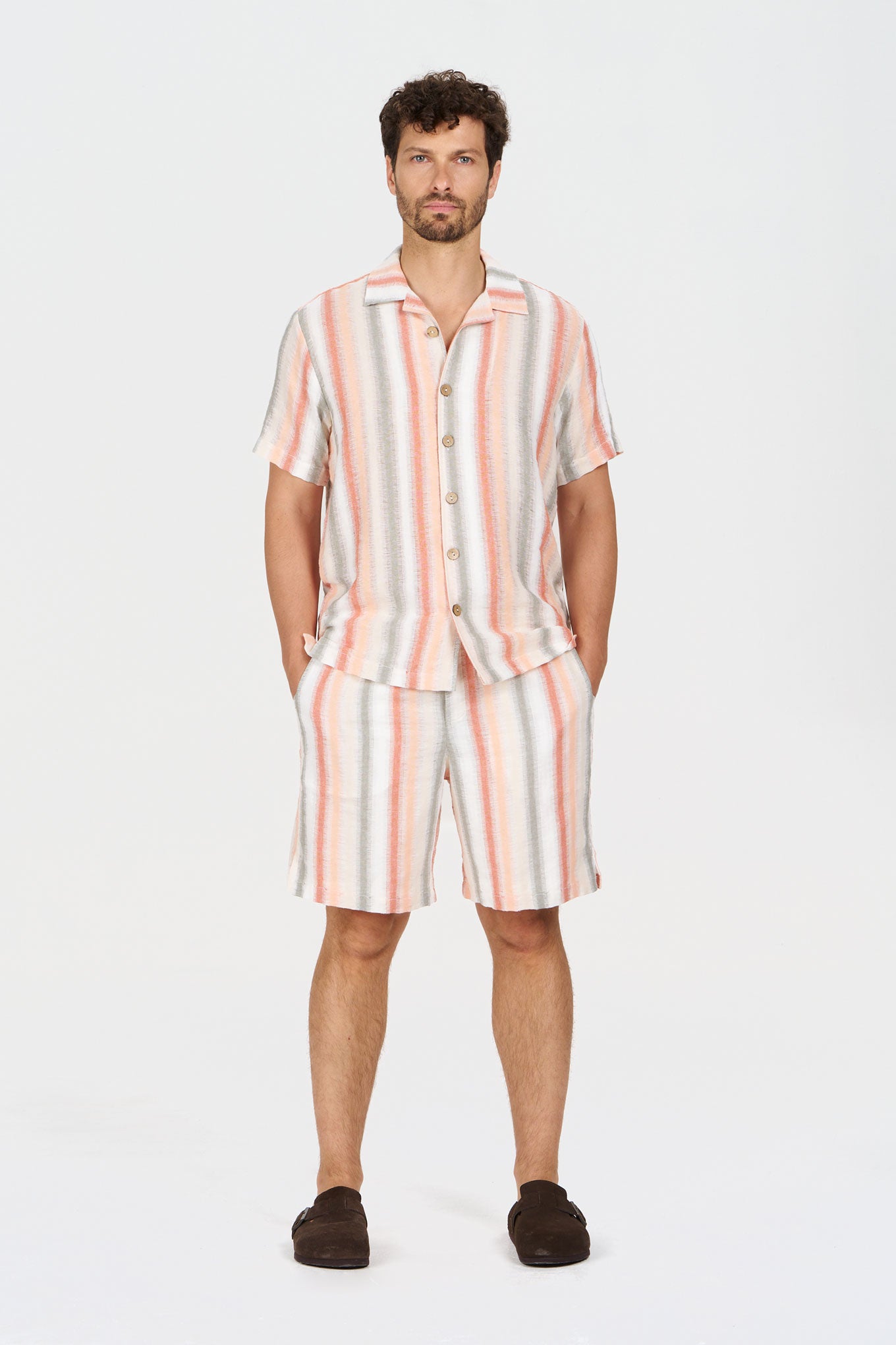 A man wearing a striped WAVE Organic Cotton Shirt with matching shorts, styled for a summer look.